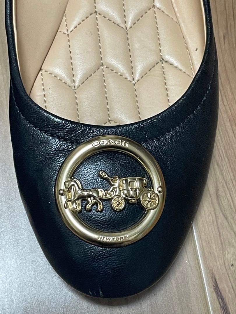 黒のフラットシューズ 金色のバッジ付き